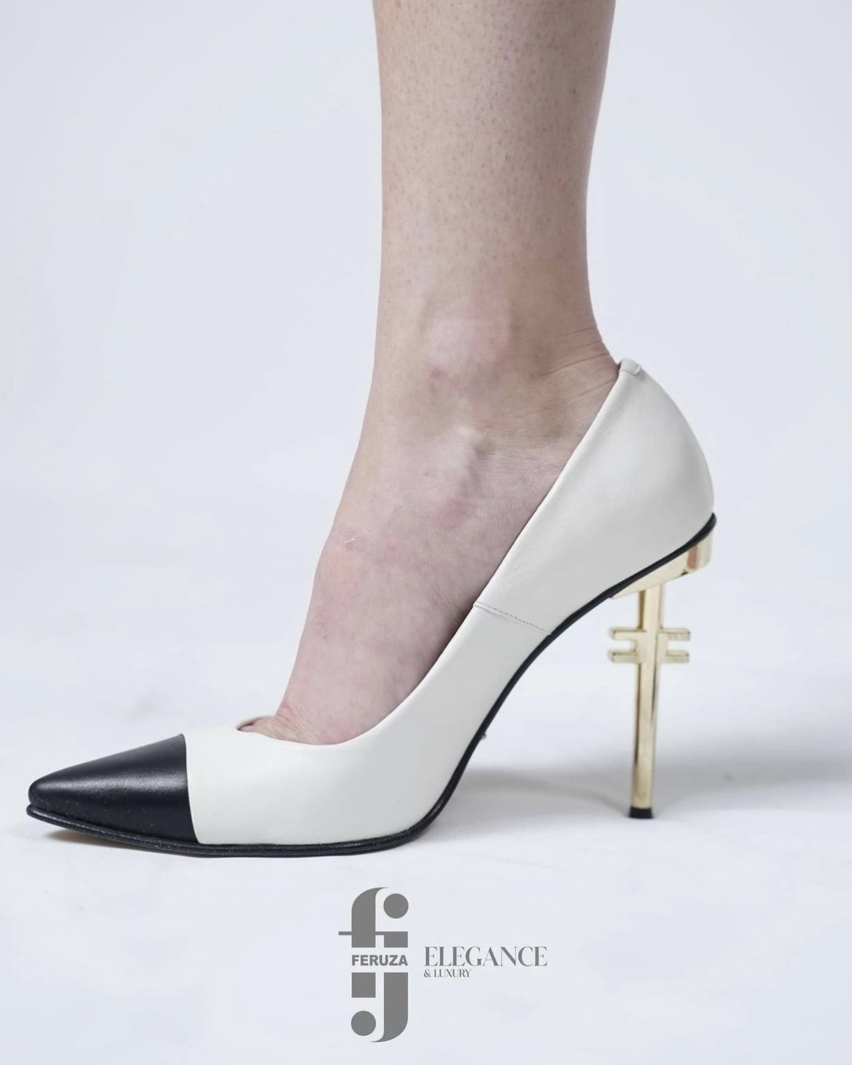 White leather stiletto with a black cap toe and the brand monogram on a gold metal heel