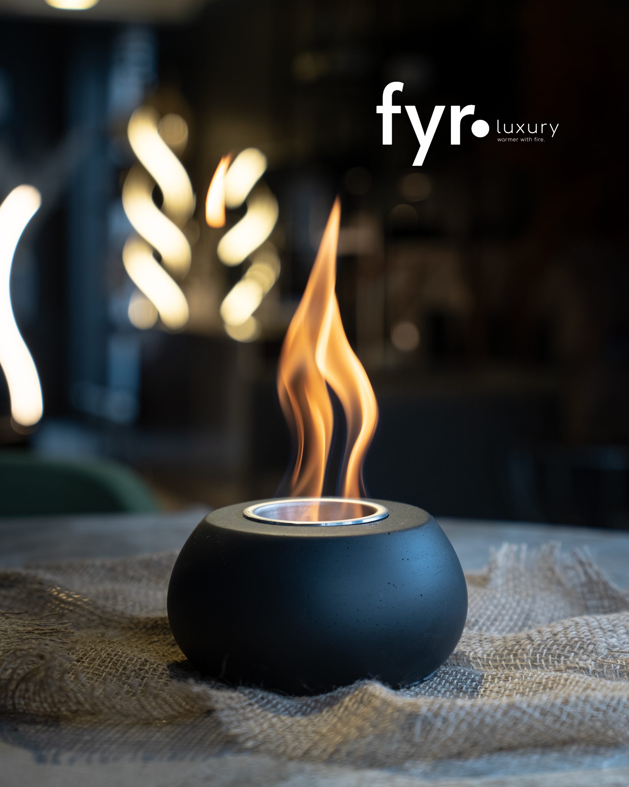 FYR Luxury product shot — flame burning in a black ceramic fire bowl with the fyr luxury logo above